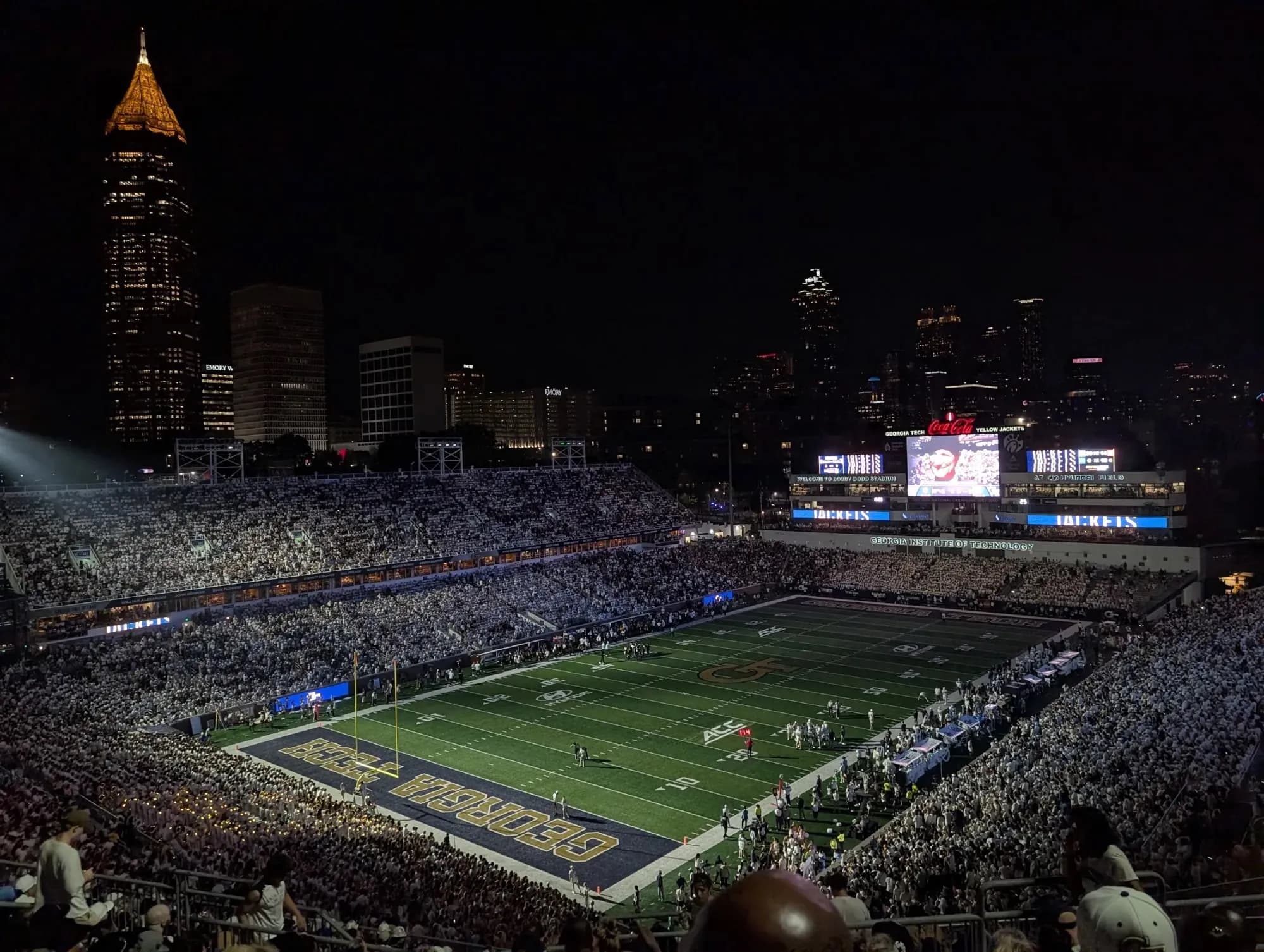 A night football game at Georgia Tech, with the Atlanta skyline behind the stadium.