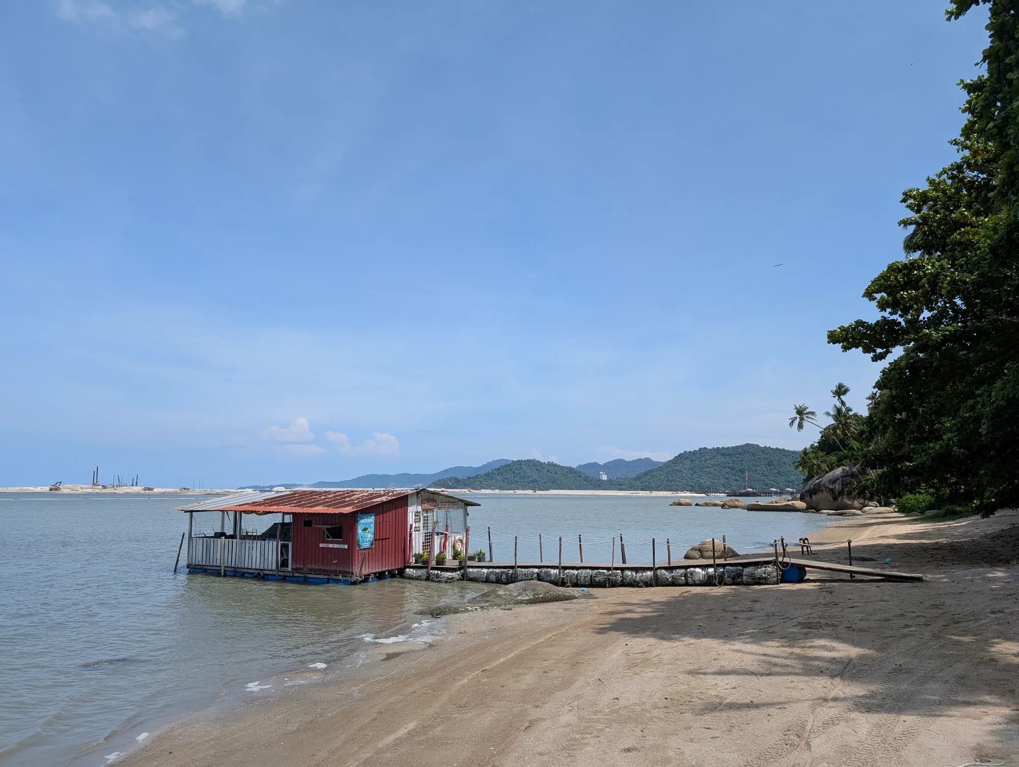 A wooden hut on stilts at the end of a jetty off a quiet beach, Penang.